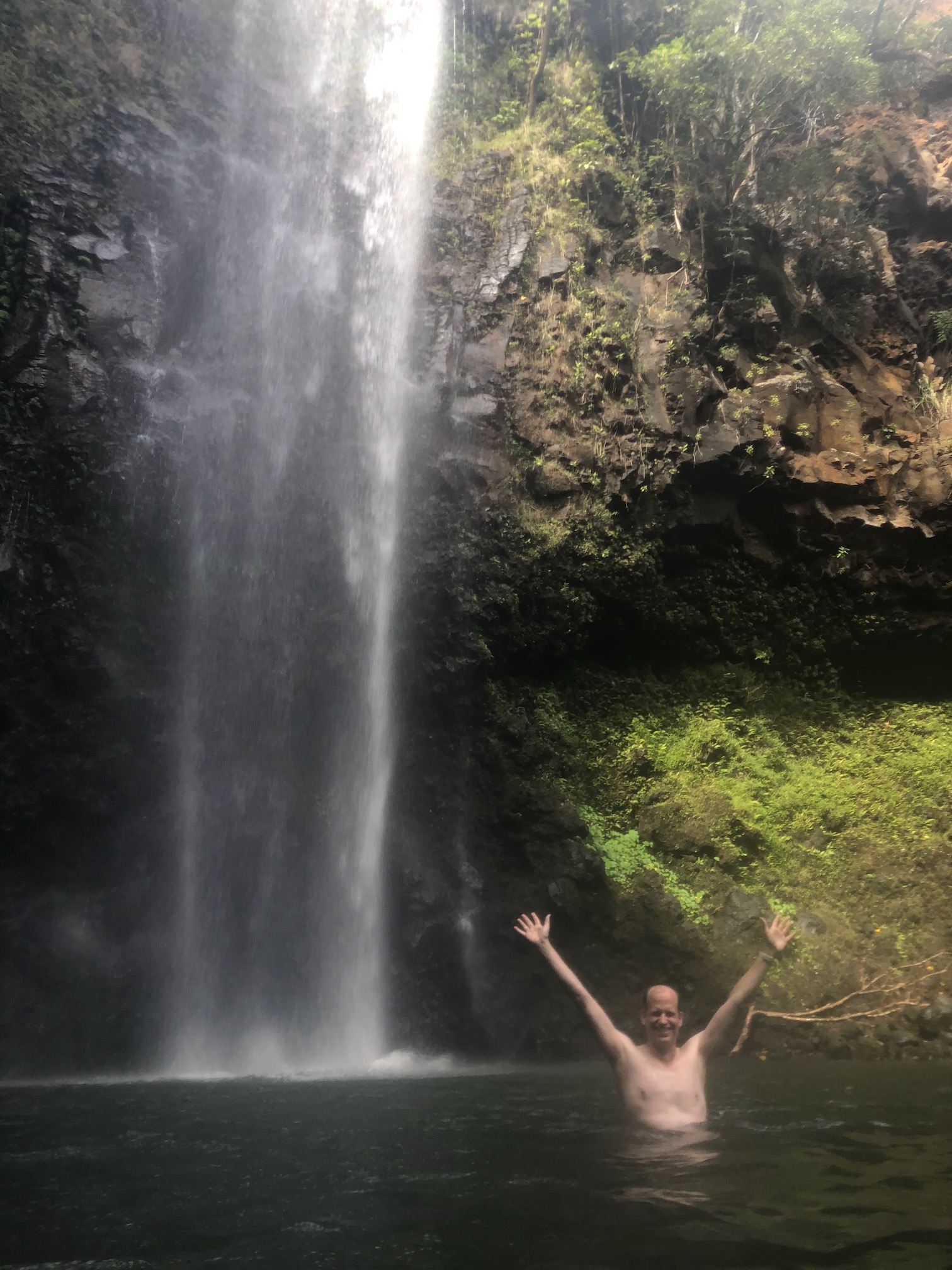 hunter with arms raised in the falls
